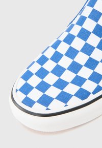 Blå och vit rutig canvas sko med svart gummisula, med en slät yta och rundad tådesign.