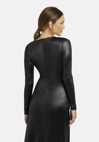 Schwarzes langärmeliges Kleid aus glattem, glänzendem Stoff. Figurbetontes Design mit hohem Halsausschnitt und einem langen, fließenden Rock.