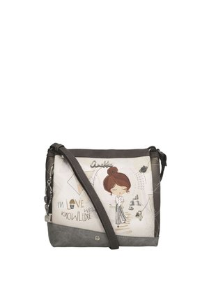 Piccola borsa a tracolla con una donna dei cartoni animati, libri e la frase "Innamorata della conoscenza" su sfondo beige e grigio.