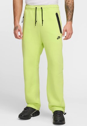 Neon grønne Nike sweatpants med sorte lynlås lommer og snøre, har en slank pasform og subtile sidesøm detaljer.