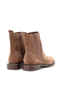 Botines de ante marrón con paneles laterales elásticos, punta redondeada y un tacón bajo apilado de madera. Lengüeta en la parte trasera para facilitar su uso.