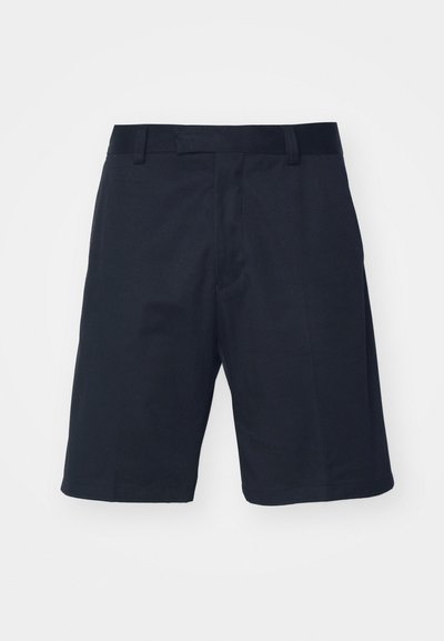 Shorts noirs en tissu lisse, avec un devant plat, des passants de ceinture et une coupe au genou, sans motifs ni éléments en métal visibles.