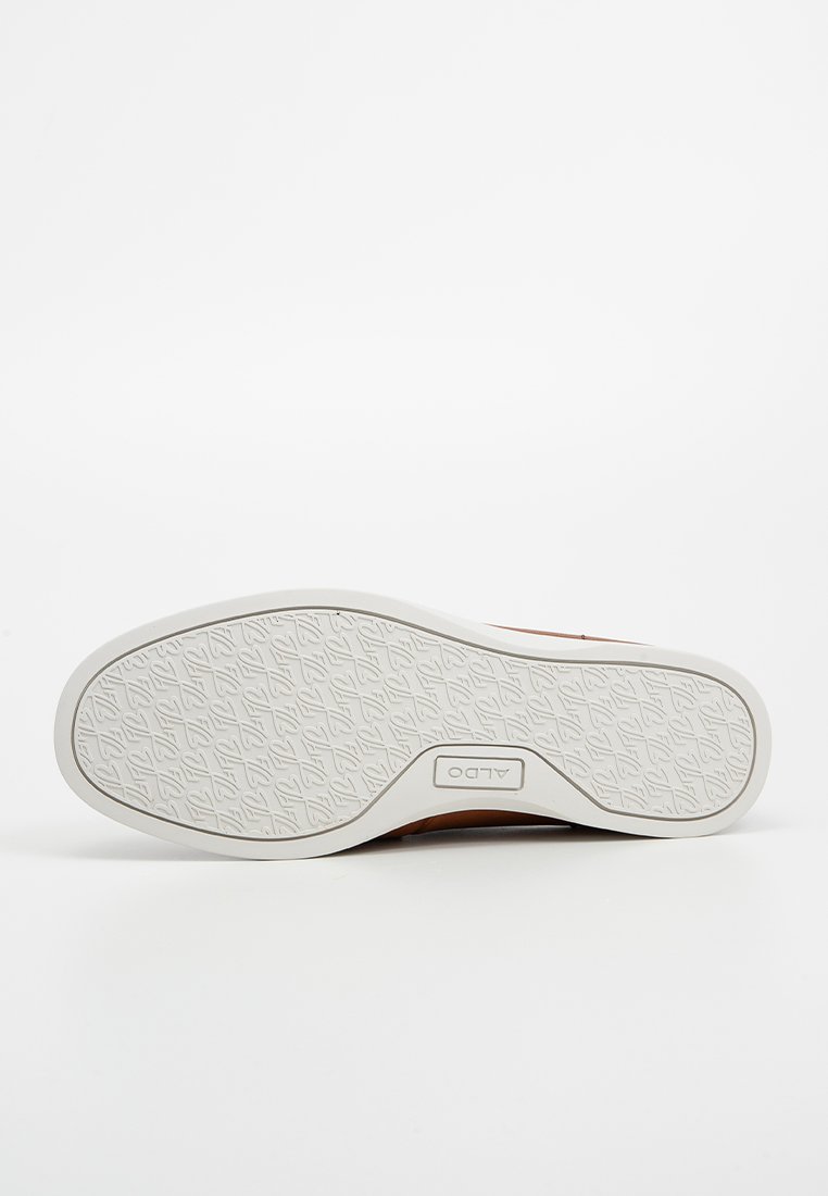 Chaussure marron clair avec tige en cuir texturé et semelle en caoutchouc blanche contrastante, dotée d'un profil à motif et du logo de la marque.