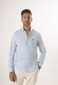 Helles blaues Button-Down-Hemd mit langen Ärmeln, schlanke Passform, mit kleinem navy Logo auf der linken Brust und einem Kentkragen-Design.