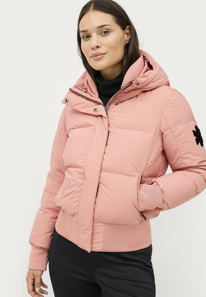 Lyserød puffer jakke med hætte, med lynlås foran, ribbede manchetter og et sort broderet logo på ærmet.