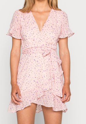 Rosa blumiger Wickelkleid mit kurzen Rüschensäumen, V-Ausschnitt und einem Bindegürtel. Es hat einen rüschensaum und verstreute kleine lila und gelbe Blumen.