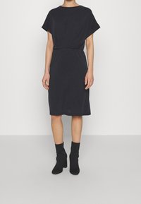 Schwarzes knielanges Kleid mit kurzen Ärmeln, einem lockeren Schnitt und einer gerafften Taille. Verfügt über einen weichen Stoff und einen einfachen runden Ausschnitt.