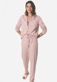 Lichtroze pyjama set met een blouse met lange mouwen en knopen, en een broek met trekkoord, beide voorzien van een verticale bloemenprint.
