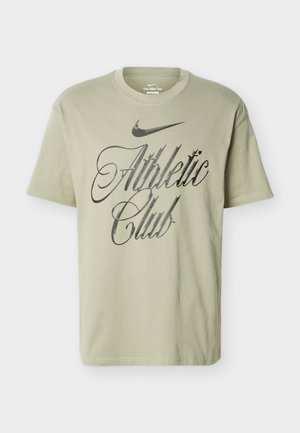 Hele roheline Nike T-särk musta "Athletic Club" kirjaga ja musta Nike Swooshi logoga teksti kohal esiküljel.