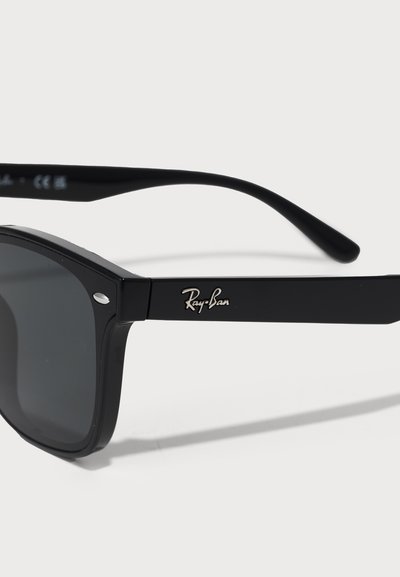 Черни слънчеви очила Ray-Ban с правоъгълни стъкла, солиден черен рамка и сребристо лого на дръжката. Характеризират се с тъмно оцветени стъкла и класически дизайн.