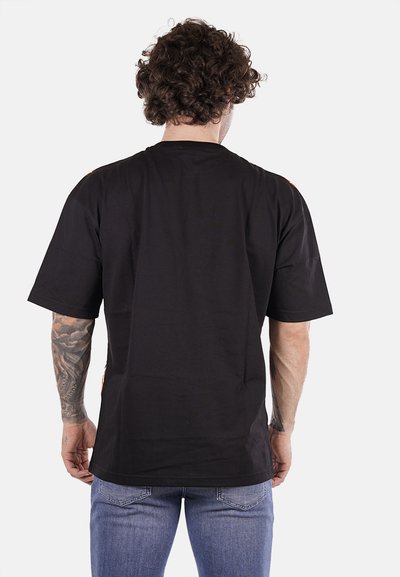 T-shirt nera a maniche corte in cotone, con una vestibilità rilassata e sottili accenti rossi sulle spalle. Texture liscia, design casual.