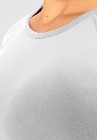 Helles graues, tailliertes T-Shirt mit rundem Halsausschnitt und gerippten Abschlüssen. Glatte Textur mit dezenten Nähdetails.
