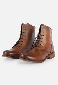 Botas de cuero marrón hasta el tobillo con punta redonda, diseño de cordones y un acabado liso y pulido. Presenta un tacón de madera bajo.