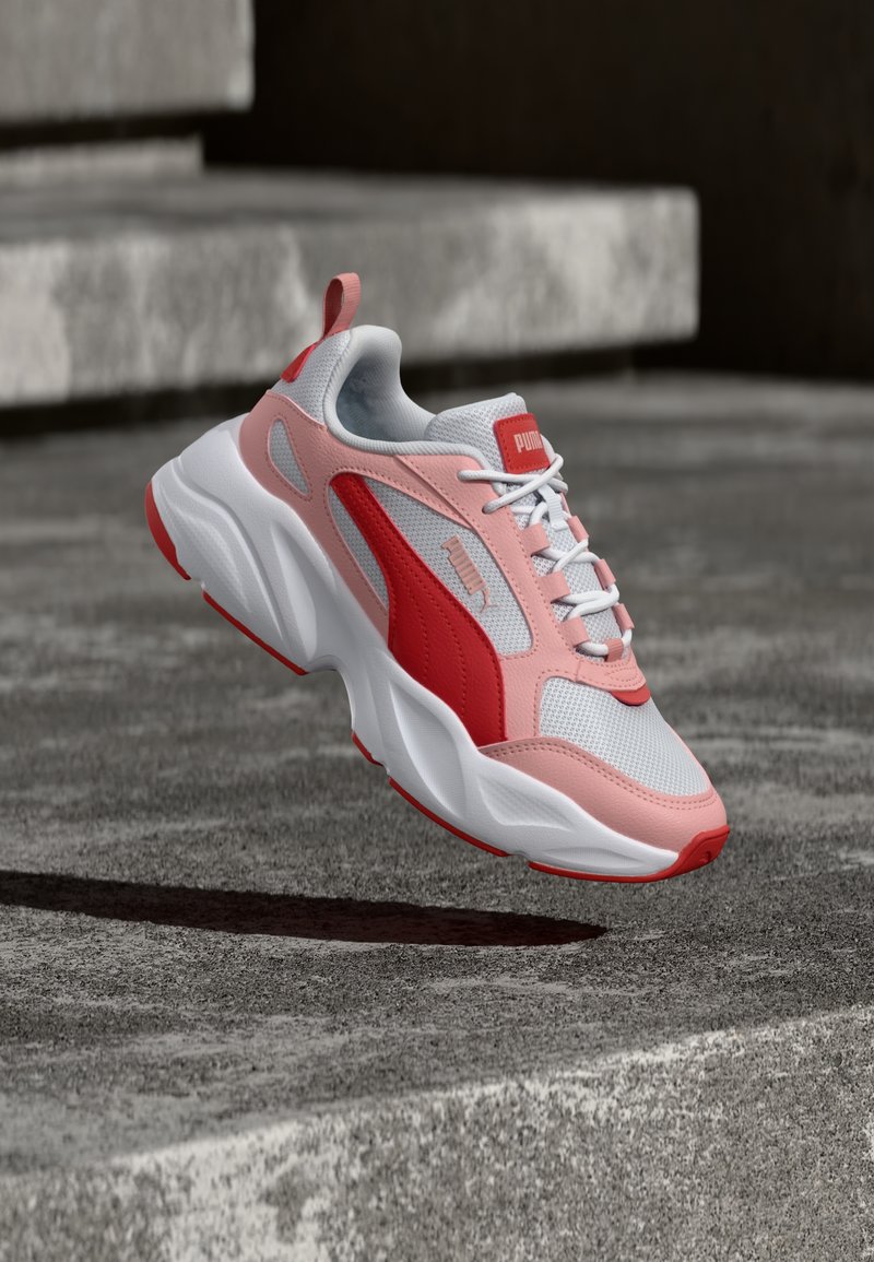 Puma-sneakers in roze en rood, met een mesh bovenwerk, witte zool, gevoerde kraag en gestructureerde accenten. Lichtgewicht ontwerp met veters.
