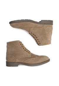 Stivaletti in camoscio color cuoio con un design brogue, punta tonda, lacci color cuoio e suola in gomma con finitura testurizzata e perforazioni decorative.