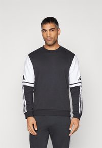 Zwarte sweatshirt met witte mouwen, voorzien van drie strepen langs de armen en een ronde hals. Gemaakt van een katoenmix.