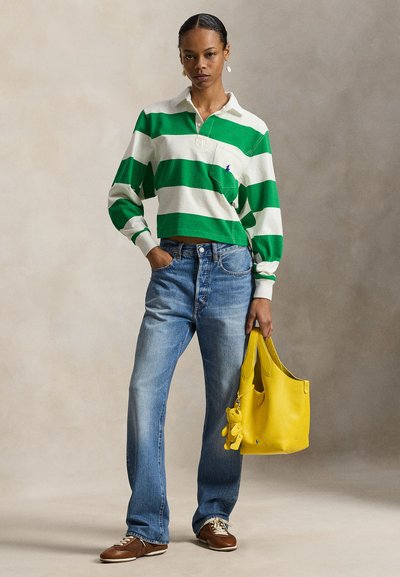 Πράσινη και λευκή ριγέ βαμβακερή μπλούζα πόλο με μακριά μανίκια, μπλε τζιν, καφέ παπούτσια και μια φωτεινή κίτρινη δερμάτινη τσάντα ώμου με μπρελόκ.