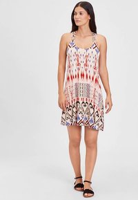 Brez naramnic poletna obleka z mešanico rdeče, modre in krem barve ter geometrijskimi vzorci; lahka tkanina, razširjena krilo in minimalna kovinska oprema.