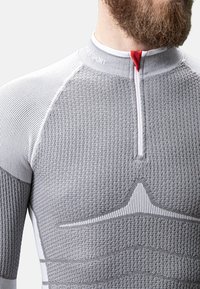 Grijs sportief long-sleeve shirt met een gestructureerd patroon, half-rits aan de voorkant en witte accenten. Heeft een aansluitend ontwerp voor optimale prestaties.