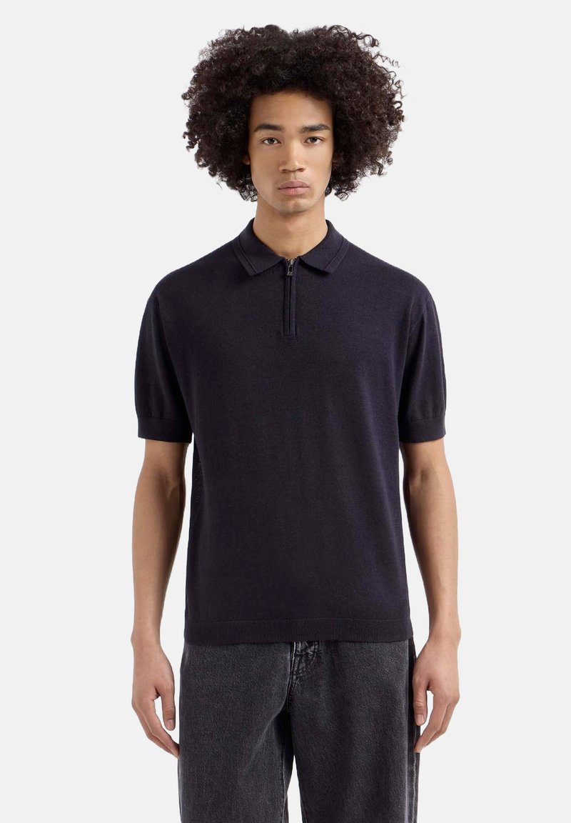 Marine polo shirt gemaakt van lichtgewicht breisel, met een ritssluiting kraag en korte mouwen, met een getailleerd ontwerp en zachte textuur.