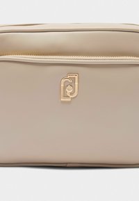 Borsa in pelle beige con una texture liscia e un logo in tonalità dorata. Il design presenta una chiusura con zip e linee pulite e minimaliste.