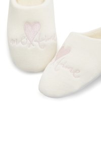 Katoenen slippers in zachte roomkleur, met een ronde neus en geborduurde roze tekst "me Time" naast een hartontwerp.