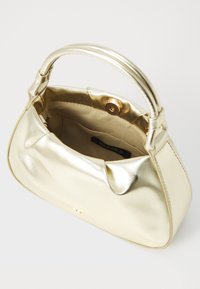 Gold metallic handbag with a curved shape, top handle, and smooth texture. Interior features a soft lining, with a logo tag visible.