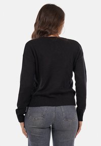 Maglione nero a maglia con maniche lunghe, polsini e orlo a coste, e una vestibilità rilassata. Il materiale appare morbido e con una texture minima. Visuale posteriore mostrata.