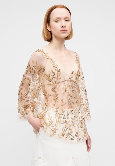 Διάφανο, κεντητό κιμονό με σχέδια φύλλων χρυσού. Ντεκολτέ σε σχήμα V και μακριά μανίκια. Μαλακό μπεζ ύφασμα με περίπλοκες λεπτομέρειες, ρέουσα σχεδίαση.