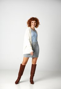 Kremowy sweter z dzianiny, jasnoniebieski dopasowany top, szara dzianinowa spódnica z guzikami i brązowe kozaki do kolan. Gładkie tekstury i warstwowy design.