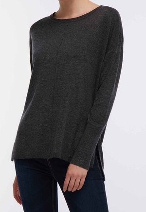Pull en tricot gris foncé avec un col rond et des manches longues, présentant des fentes sur les côtés à l'ourlet et une finition texturée.