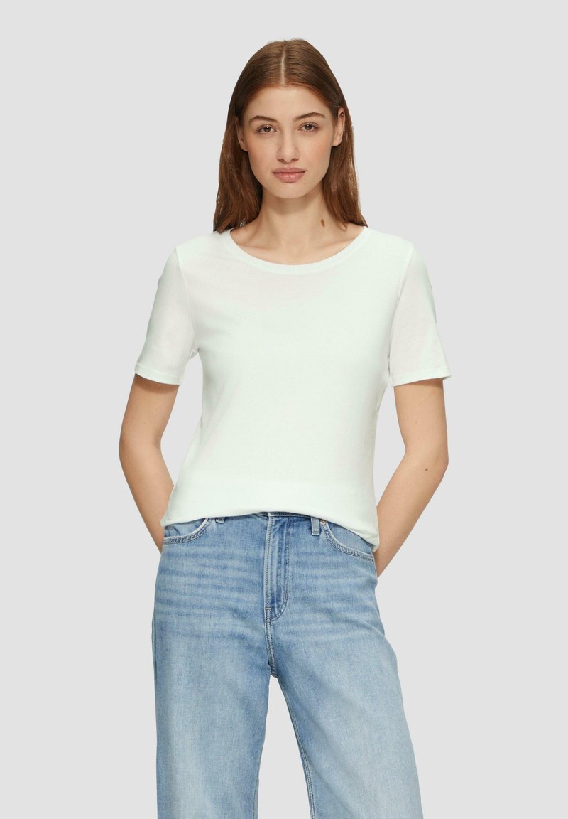 T-shirt blanc à manches courtes avec un col rond, texture lisse et design ajusté, porté avec un jean en denim bleu clair.