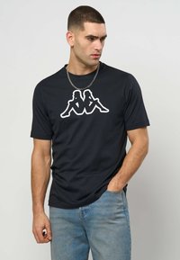 Čierne tričko s krátkym rukávom, na hrudi má biely grafický logotyp. Tričko je vyrobené z hladkej látky a má voľný strih.