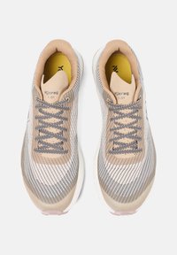Beige athletic shoes with a mesh upper, striped pattern, and grey laces. Cushioned insole, flexible sole, and minimalistic design.