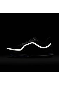 Basket noire avec une bande courbée réfléchissante blanche le long du côté et des lacets noir et blanc à motifs sur un fond sombre.