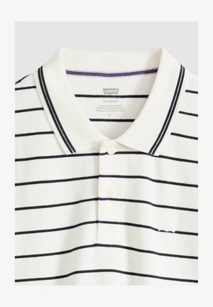 Polo blanco de Levi's con rayas horizontales negras, tapeta con dos botones y cuello con detalles de ribete negro.