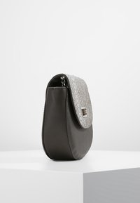 Szara skórzana torba na ramię z teksturowanym, jasnoszarym klapkiem. Posiada srebrny zamek i zaokrąglony kształt, z gładkim wykończeniem.