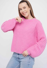 Rosa, gerippter Strickpullover mit runder Halslinie, langen Ärmeln und lockerer Passform. Die Textur wirkt weich und flauschig, mit ausgeprägten horizontalen Linien.