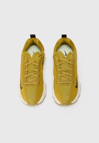 Sapatos de desporto amarelos com um cabedal em malha e têxtil, apresentando acentos pretos, bico arredondado, perfurações e uma sola almofadada.