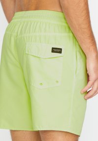 Costumi da bagno verde lime con vita elastica, tasche laterali e una tasca con pattina sul retro con una toppa nera con il logo Volcom.
