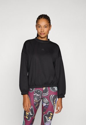Felpa nera con collo alto e orlo elasticizzato, caratterizzata da maniche lunghe e un piccolo logo sul petto. Abbinata a leggings con motivo a farfalla.