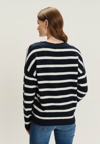 Sweter w granatowo-białe paski, wykonany z miękkiego materiału, z okrągłym dekoltem i luźnym krojem, z kontrastującymi szerokimi poziomymi paskami.