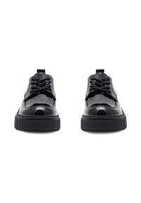 Para czarnych błyszczących skórzanych butów na sznurowadła z grubymi gumowymi podeszwami, widziana od przodu na białym tle.