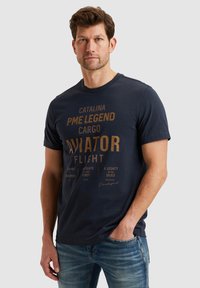 Marineblauwe katoenen t-shirt met een geprint ontwerp in goud en witte tekst, ronde hals, korte mouwen en een relaxte pasvorm.