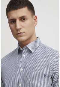 Camicia a righe blu navy e bianca, con collo, taschino sul petto e piccolo logo ricamato. Tessuto dalla texture liscia.