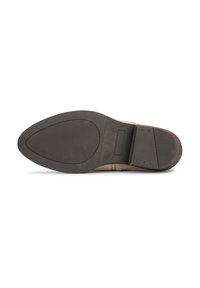 Suela de un zapato con una parte inferior de goma negra con un agarre texturizado, forma curvada y parte superior de ante beige claro con detalles de costura.
