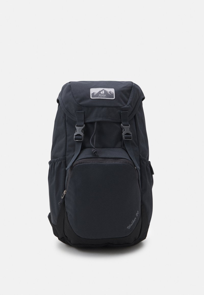 Sac à dos noir avec des bretelles réglables, un rabat supérieur, une poche zippée à l'avant et des poches en mesh sur les côtés. Fabriqué en tissu durable avec une texture lisse.