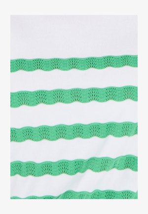 Weißer Stoff mit grüner, gewellter Stickerei in einem sich wiederholenden Wellenmuster, das aufwendige Details und Textur zeigt.