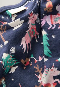 Blauwe stof met kleurrijke feestelijke illustraties, waaronder eenhoorns, bomen en sneeuwvlokken. Zachte, gestructureerde material.