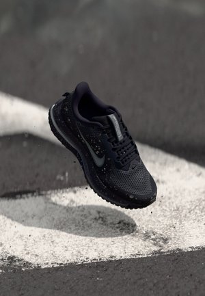 Nike running shoe in dark blue with a breathable mesh upper, textured sole, and reflective accents. Features scattered paint splatter details.